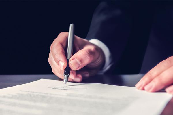 Distinction recueil des volontés et testament : Main d'un homme qui tient un stylo à plume et signe un testament