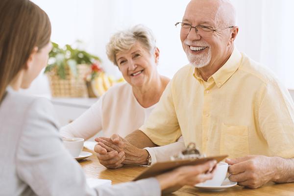 Couple de séniors qui discute avec une conseillère autour d'une table