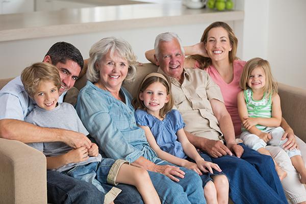 Plusieurs générations souriantes d'une famille assisent sur un canapé