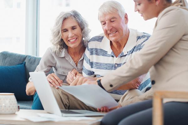 Droits succession France et pays occidentaux : Couple de séniors consultant un document avec une conseillère dans le salon