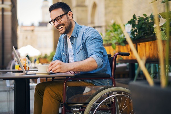Homme handicapé souriant assis dans un café et buvant un café.