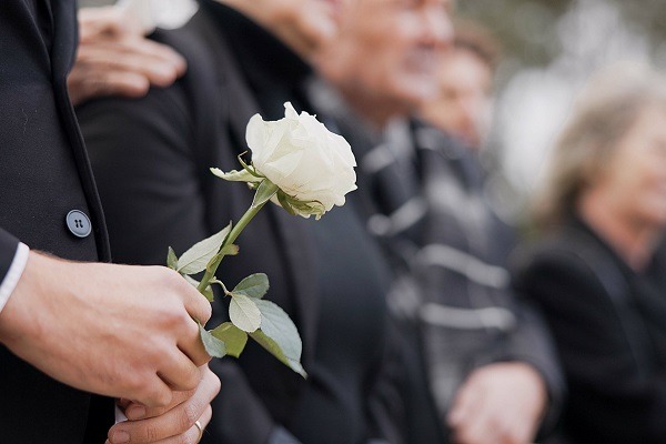 une main qui tient une rose blanche pour des obsèques