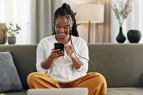 Une femme noire heureuse et une carte de crédit avec un téléphone sur un canapé pour les achats en ligne, le code de paiement et la fintech à la maison. Banque mobile, finance et mot de passe pour mettre à jour l'abonnement, le commerce électronique et les économies d'argent.