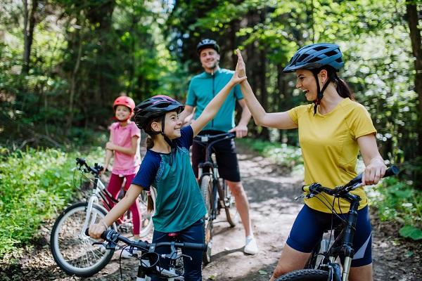famille de deux adulte et deux enfants qui font du vélo dans les bois
