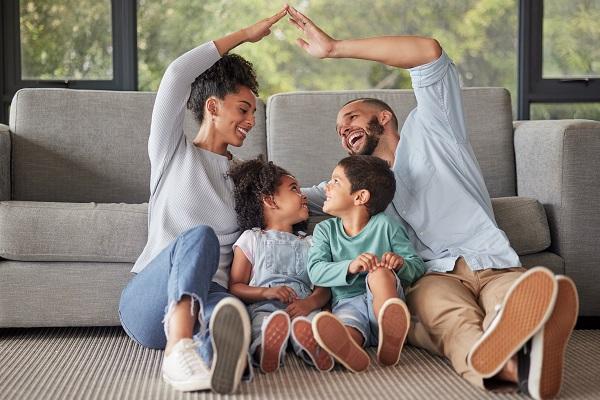 un couple avec ses deux enfants qui sont assis par terre et qui rigolent