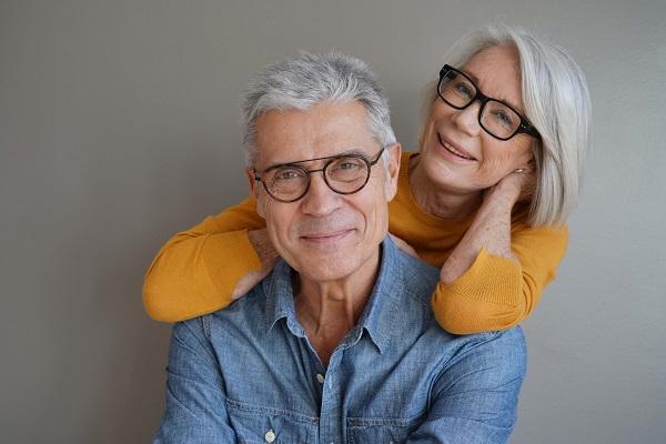 Garanties prévoyance obsèques : un couple de quinquagénaires portant des lunettes et souriant