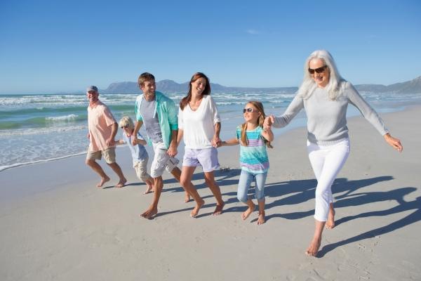 Une famille avec parents, enfants et grands parents, se baladent sur la plage