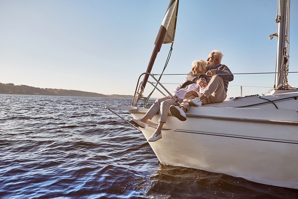 Amoureux de la voile. Un couple de seniors heureux assis à bord d'un voilier sur une mer bleue et calme. Homme serrant sa femme dans ses bras tout en profitant de la vue